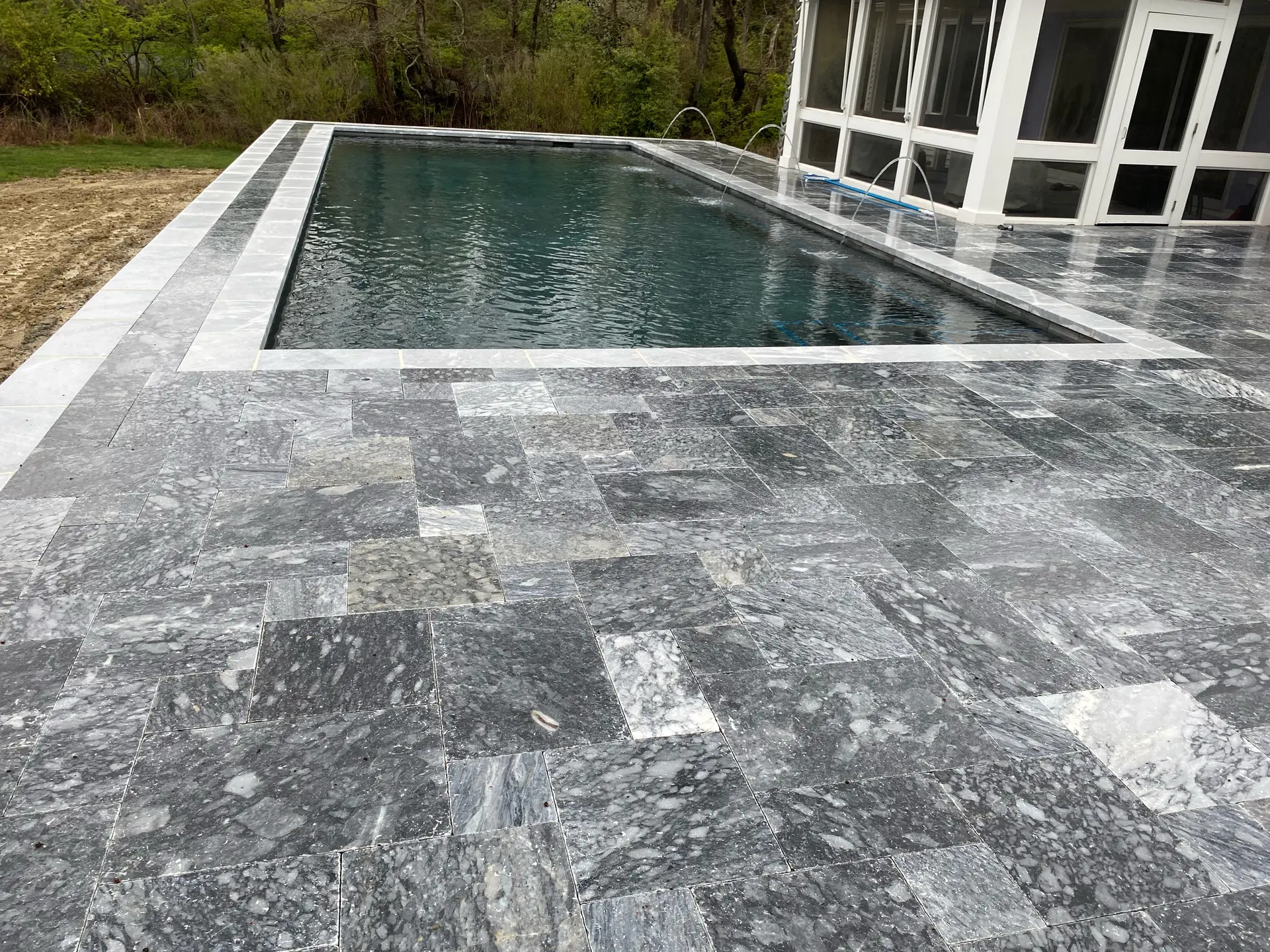 Luxury marble pool patio with grey stone pavers framing a clean rectangular pool